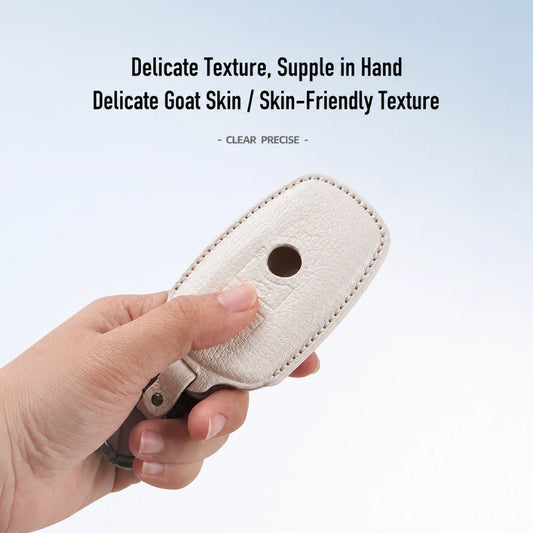 A hand holding a cream-colored, textured goat skin key fob cover against a light blue gradient background, with promotional text at the top.