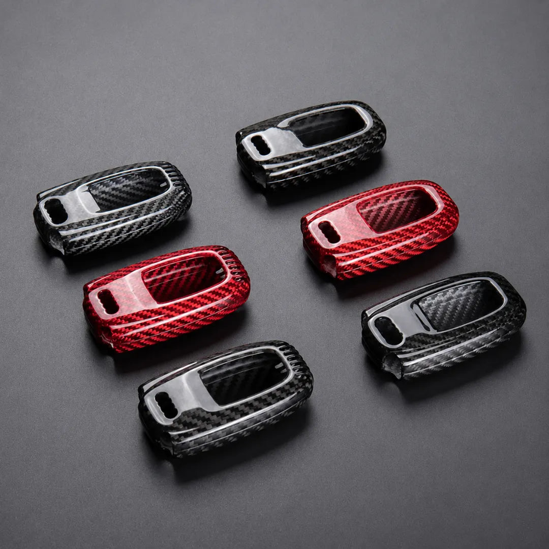 Six carbon fiber textured car key fob cases in black, red and black, arranged on a dark gray background.