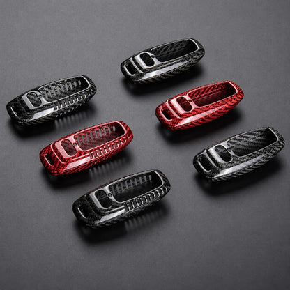 Six glossy carbon fiber pattern car key fob  covers in black, red and silver, arranged on a dark gray background.