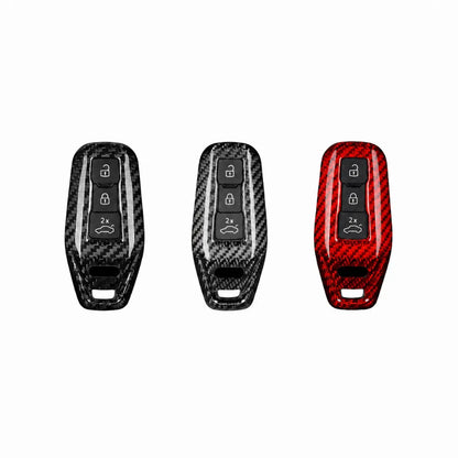 Three carbon fiber key fob covers shown side by side on a plain white background, with black/gray carbon fiber patterns on the left two and a red carbon fiber pattern on the right.