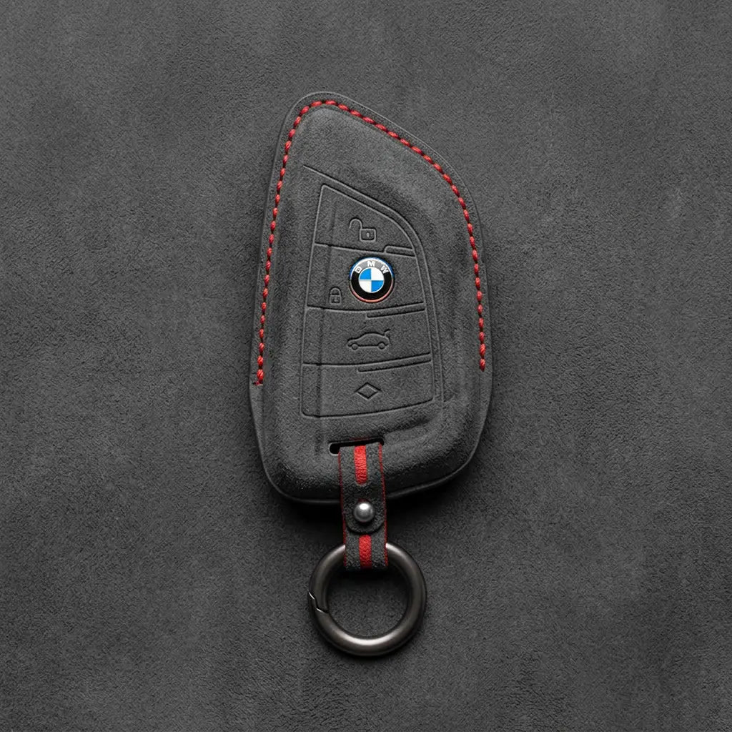 Black Alcantara key fob cover with BMW logo on a dark gray background