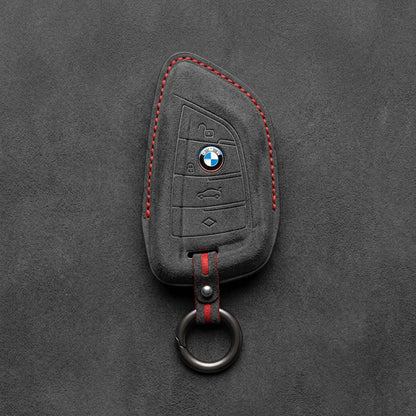 Black Alcantara key fob cover with BMW logo on a dark gray background