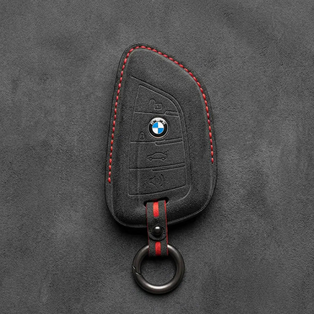 Black Alcantara key fob cover with BMW logo on a dark gray background