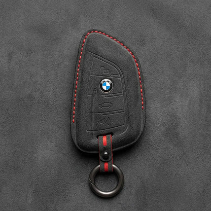 Black Alcantara key fob cover with BMW logo on a dark gray background