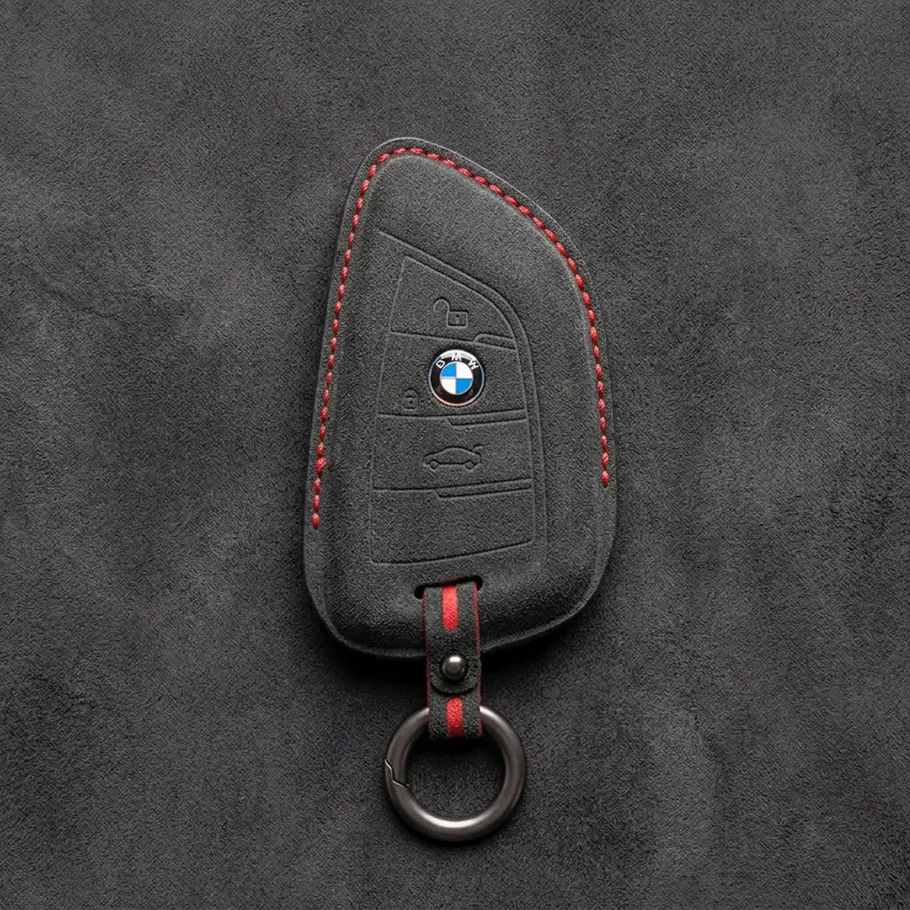 Black Alcantara key fob cover with BMW logo on a dark gray background
