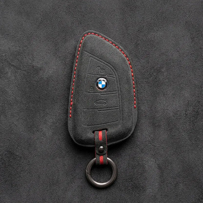 Black Alcantara key fob cover with BMW logo on a dark gray background
