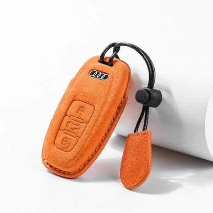An orange suede car key fob cover with a black keychain strap and a matching leather tag, shown on a clean white background.