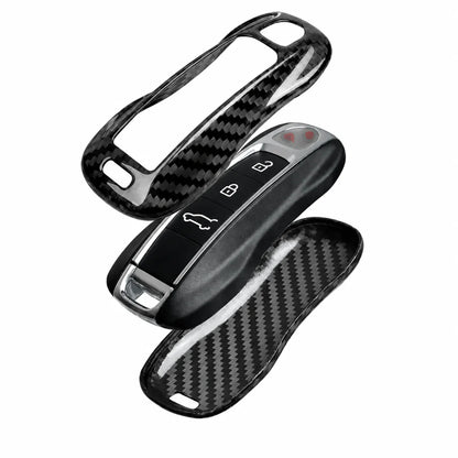 A carbon fiber patterned key fob cover shown in three pieces, including one fitted over a key fob and two loose pieces displaying the textured black and gray weave pattern, on a solid white background.