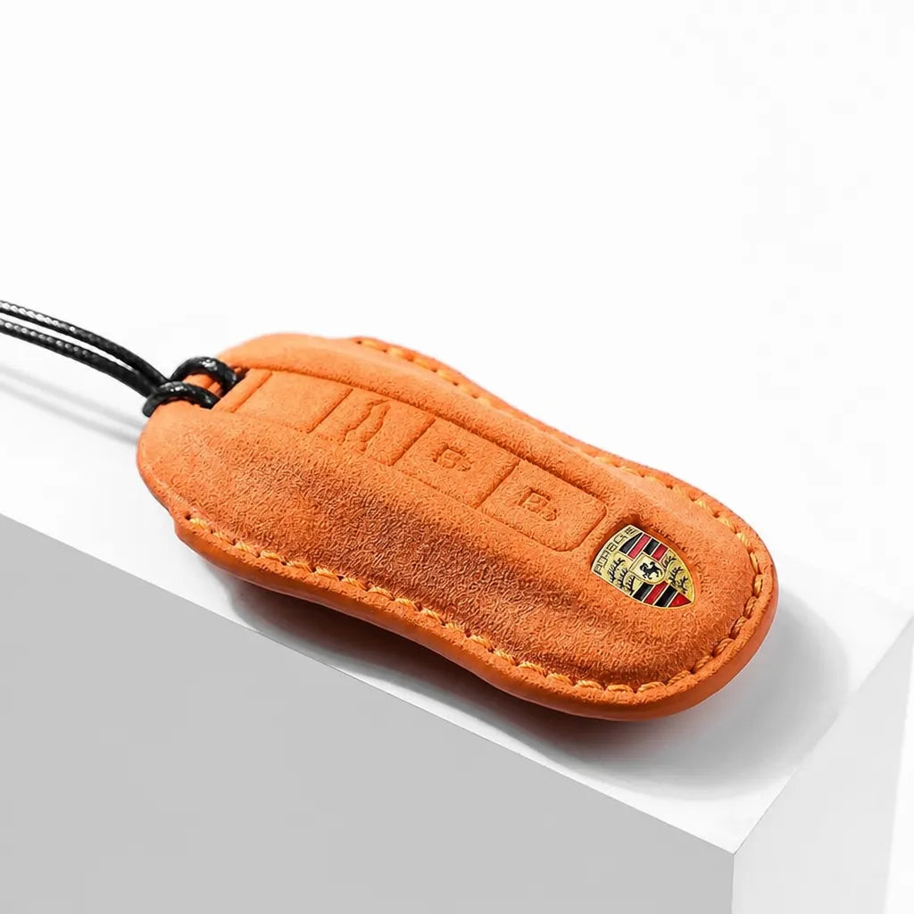 Orange suede key fob with Porsche logo on a white background