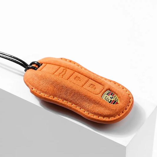 Orange suede key fob with Porsche logo on a white background