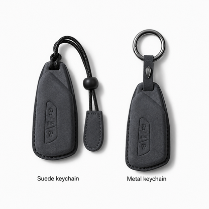 Two car keychain covers shown side by side on a light gray background: a suede keychain on the left with a black cord and bead, and a metal keychain on the right with a ring. Text below reads 'Suede keychain' and 'Metal keychain'.